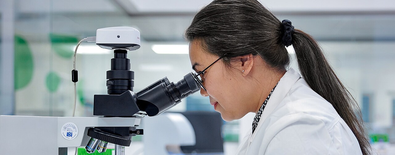 Lab specialist operates a microscope and adjusts settings to study probiotic cultures within a clean and modern laboratory