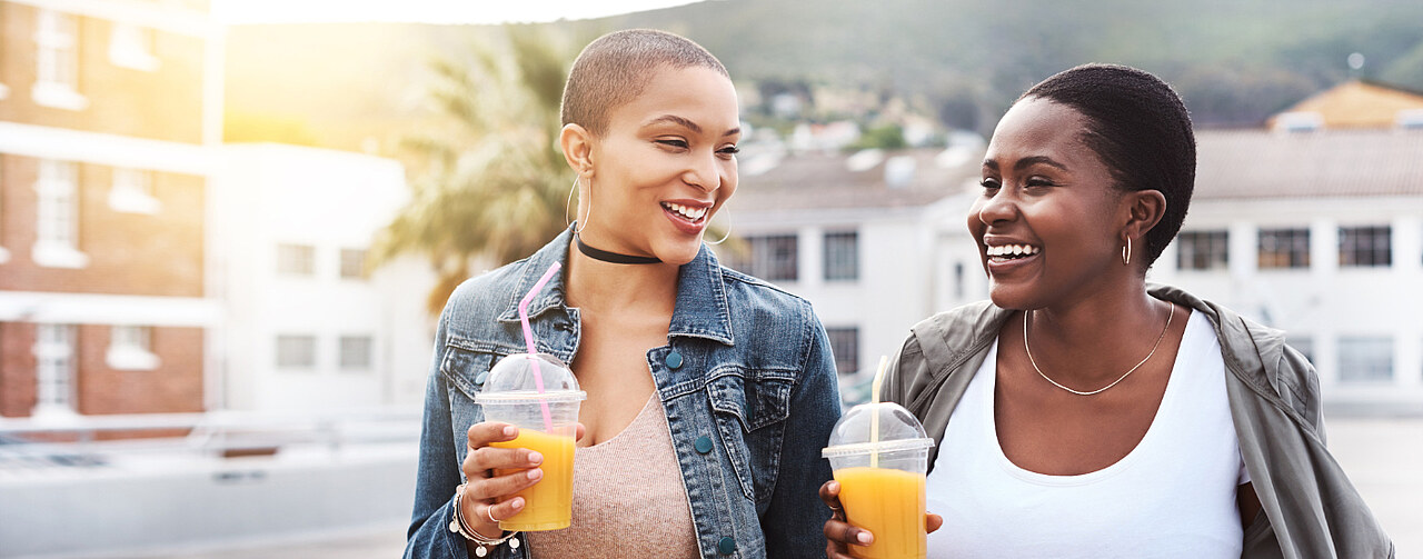 Two women drinking citrus beverages