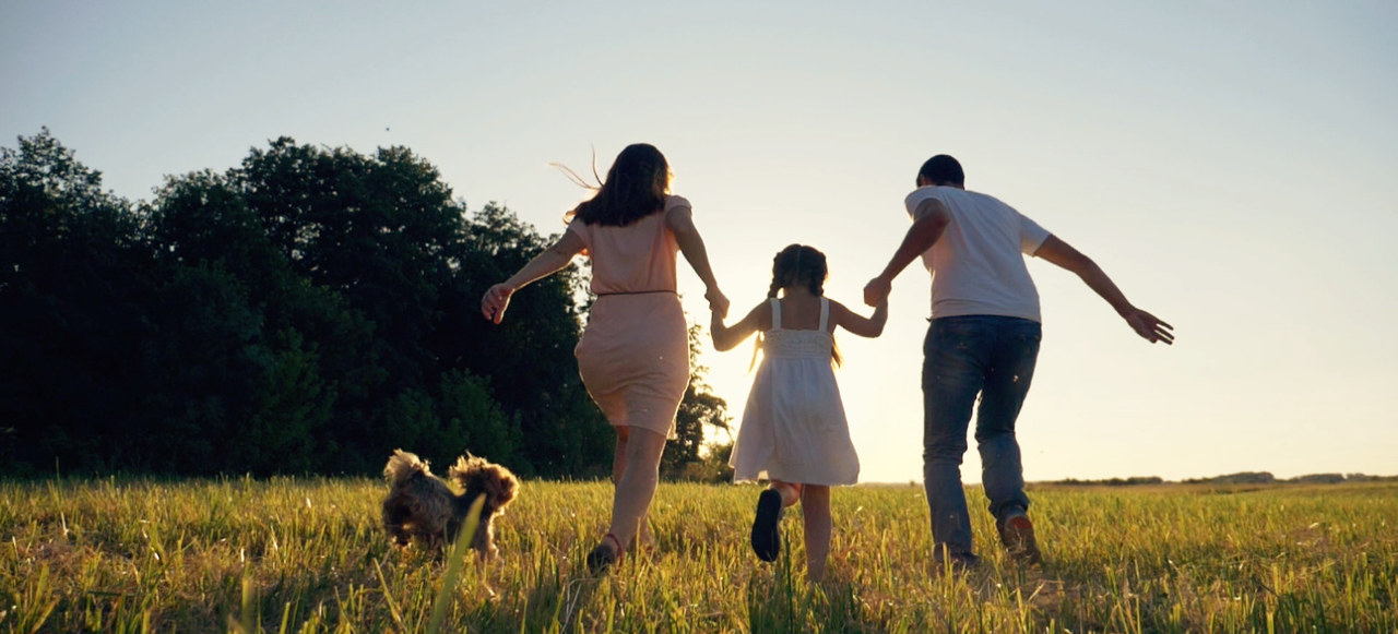 Familie mit Hund läuft über Wiese