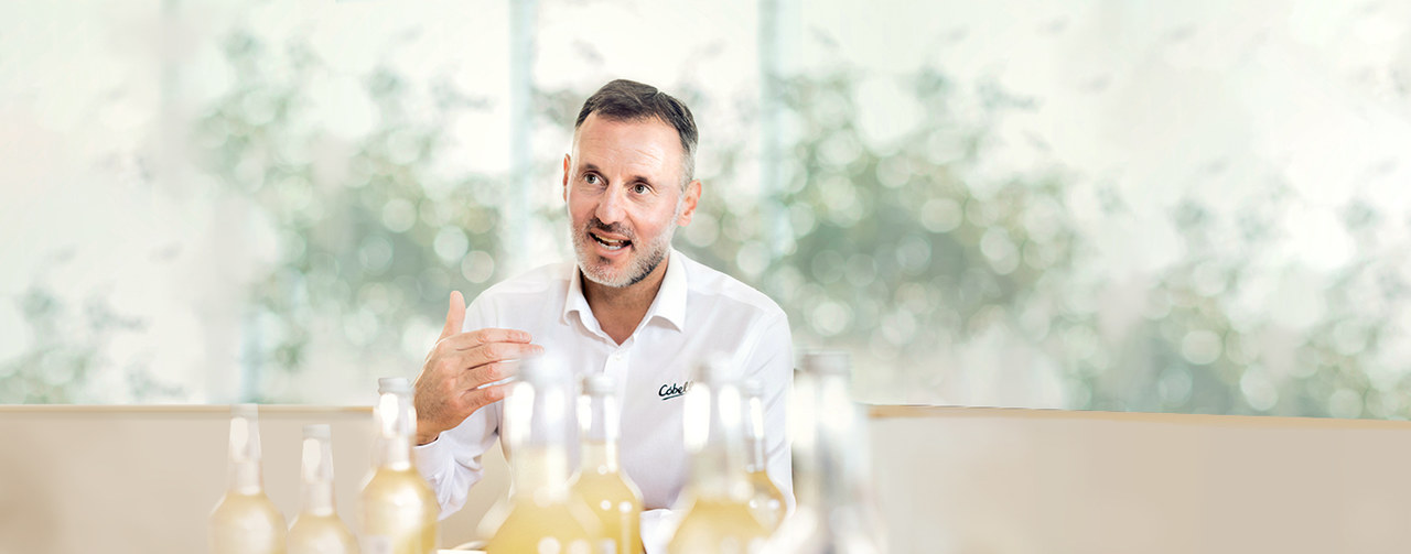 Man with white shirt in front of bottles