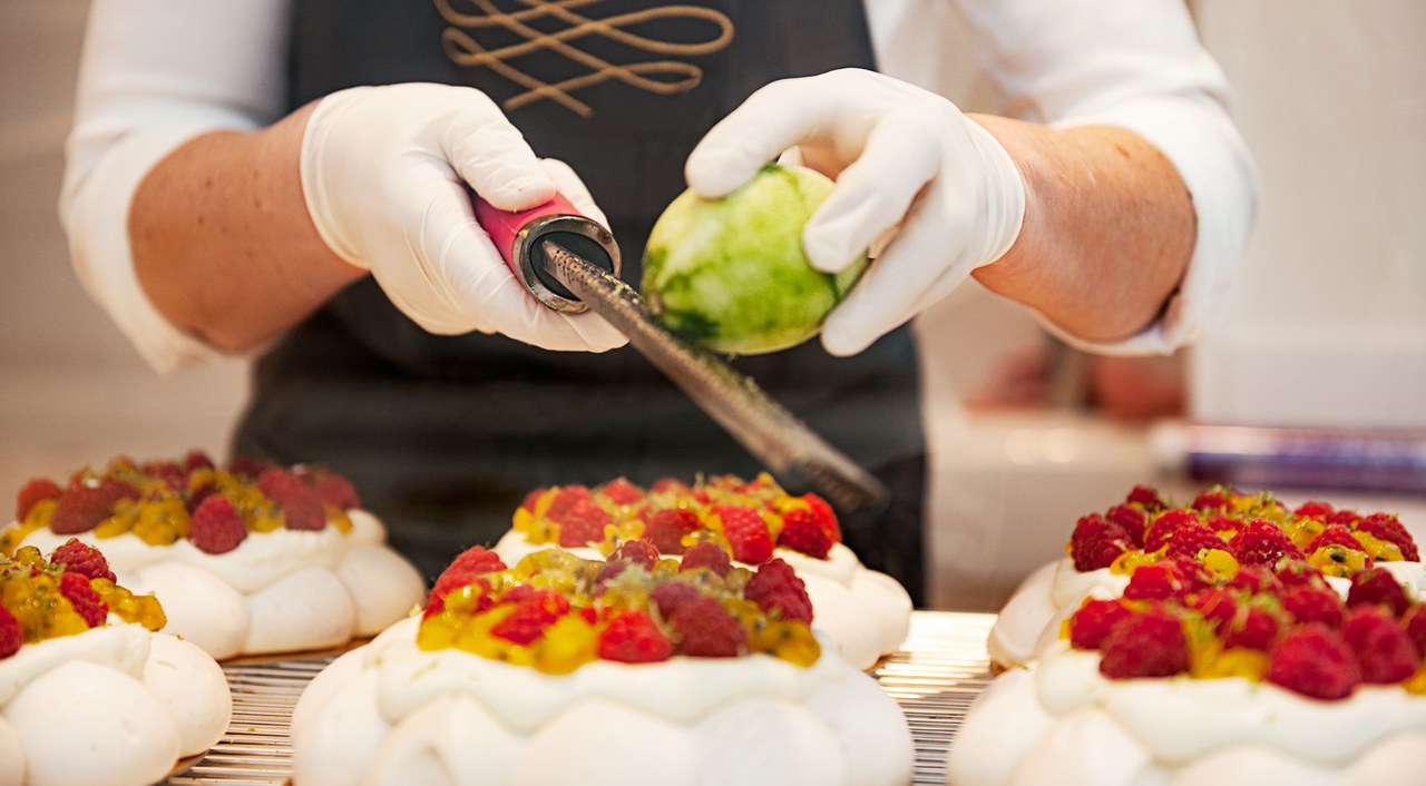 A man is grating lime over desserts.