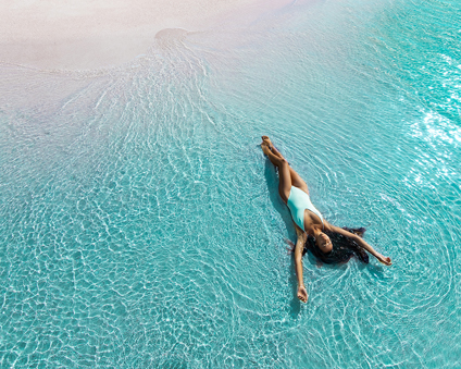 Aquaphile: summer’s calming must-have color trend Frau badet im Meer