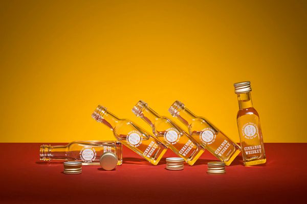 Six small, partially open, whiskey bottles are leaning against each other.