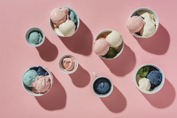 Several cups with scoop ice cream on a pink background.