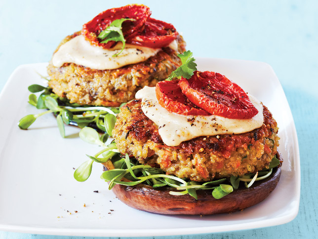 Zwei Hamburger-Buns mit vegetarischem Pattie, Gemüse und Käse auf einem Teller.