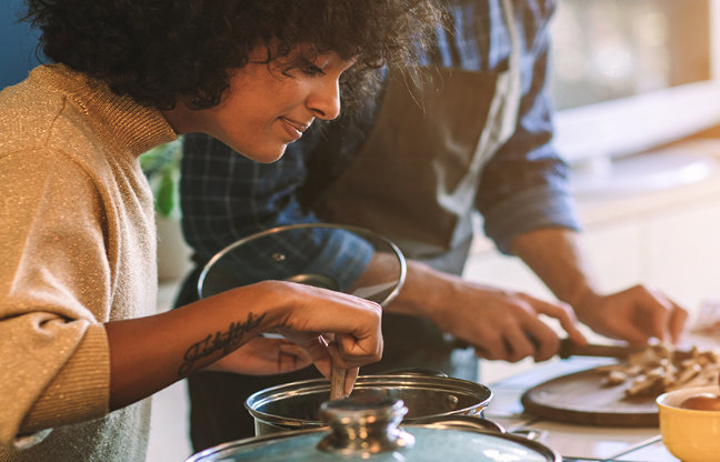 A young woman and a young man are cooking together.