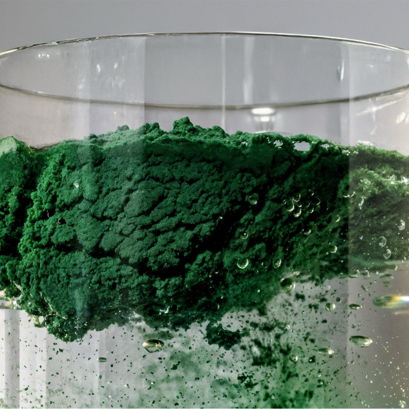 Glass with green powder in water 